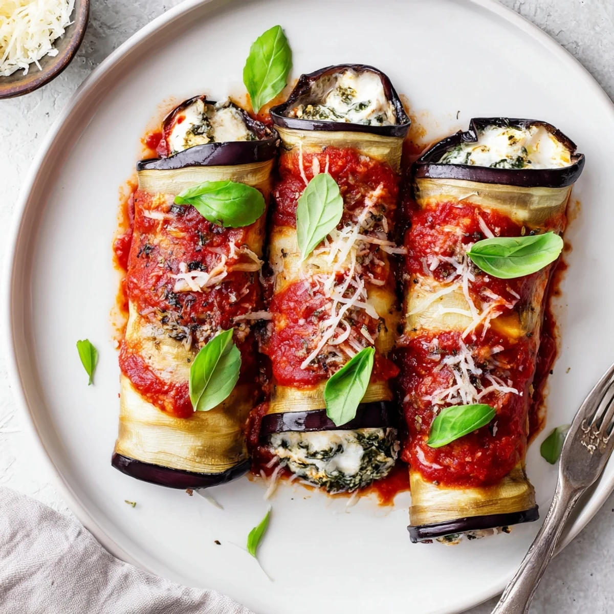 Sliced oven baked Healthy Eggplant Rollatini arranged in dish with warm marinara  