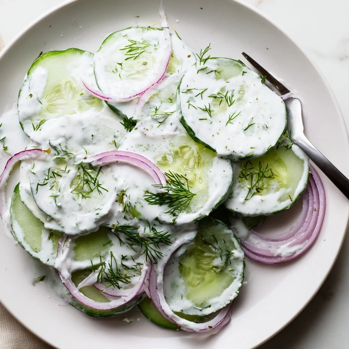 Tzatziki Cucumber Salad Recipe in a white bowl, creamy garlic dressing, dill.