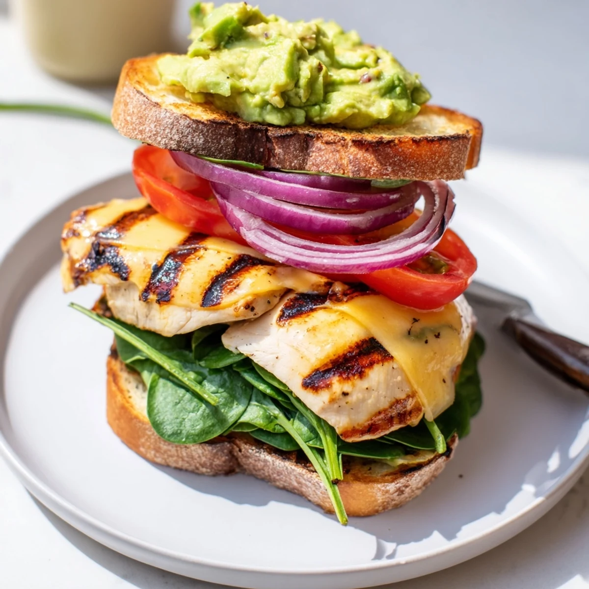 Sliced in half, creamy avocado and spinach peek inside Grilled Chicken Avocado Sandwich Recipe