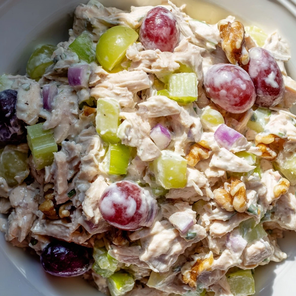 Golden chicken salad with creamy yogurt dressing features crisp celery, sweet grapes, and toasted walnuts over fresh mixed greens