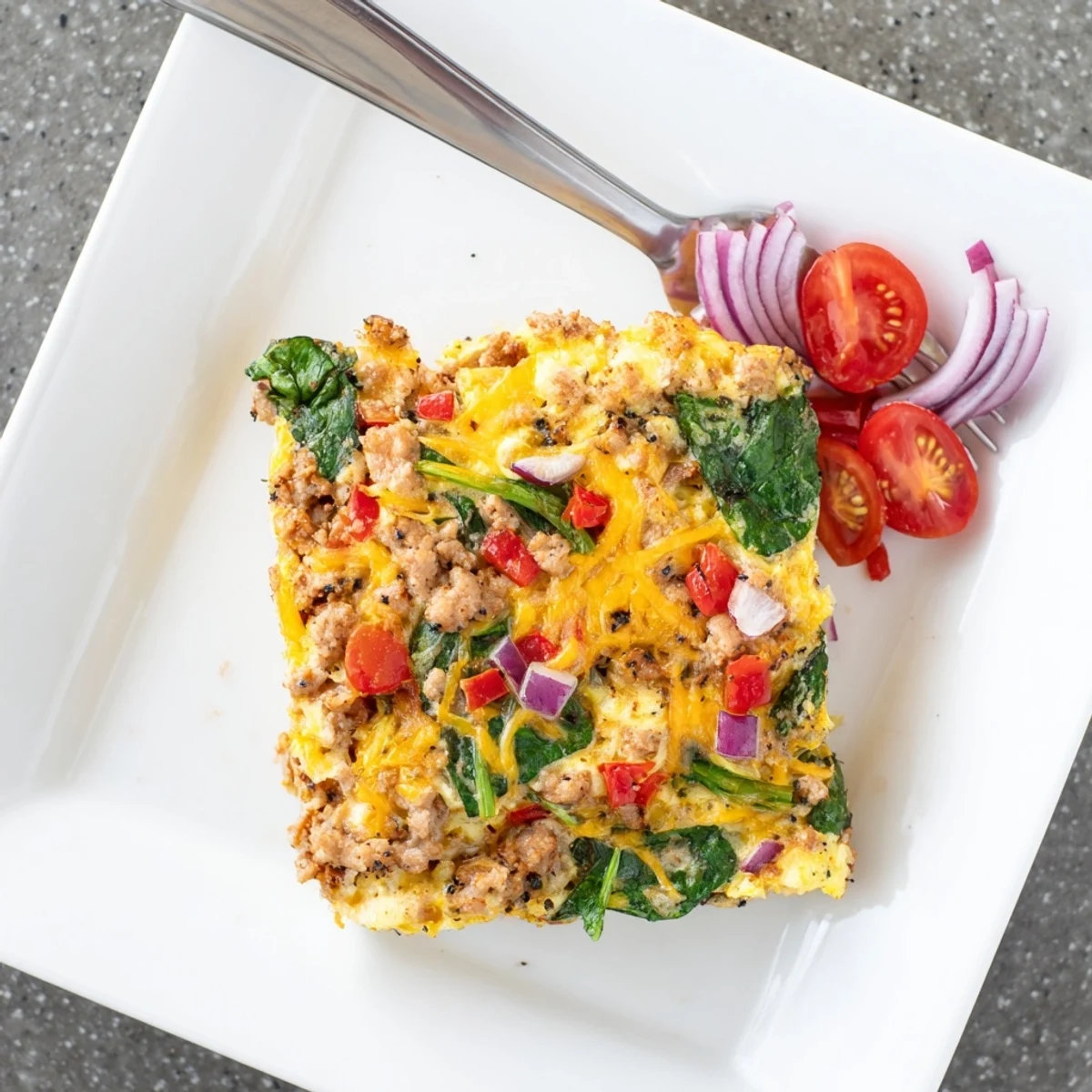Warm high protein egg casserole serving with cottage cheese tomatoes and melted cheese on a white plate