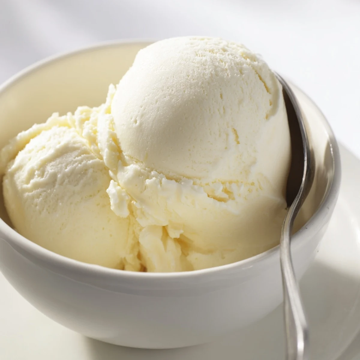 Rich custard-based vanilla ice cream recipe swirled in metal ice cream maker canister