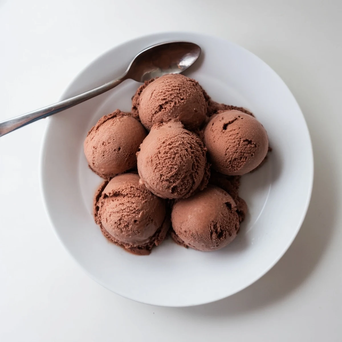 Creamy chocolate sourdough ice cream scooped into a bowl with melted dark chocolate ribbons