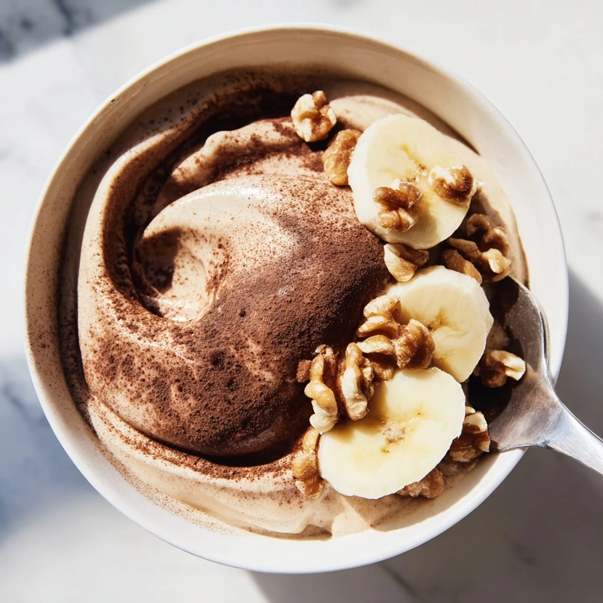 Creamy vegan healthy nice cream scooped into bowls topped with fresh berries and crunchy nuts