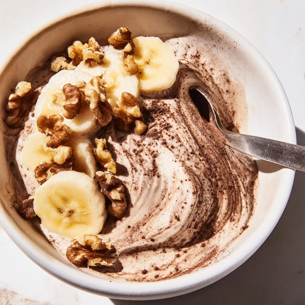 Smooth dairy-free healthy nice cream topped with cacao nibs and sliced banana on wooden board