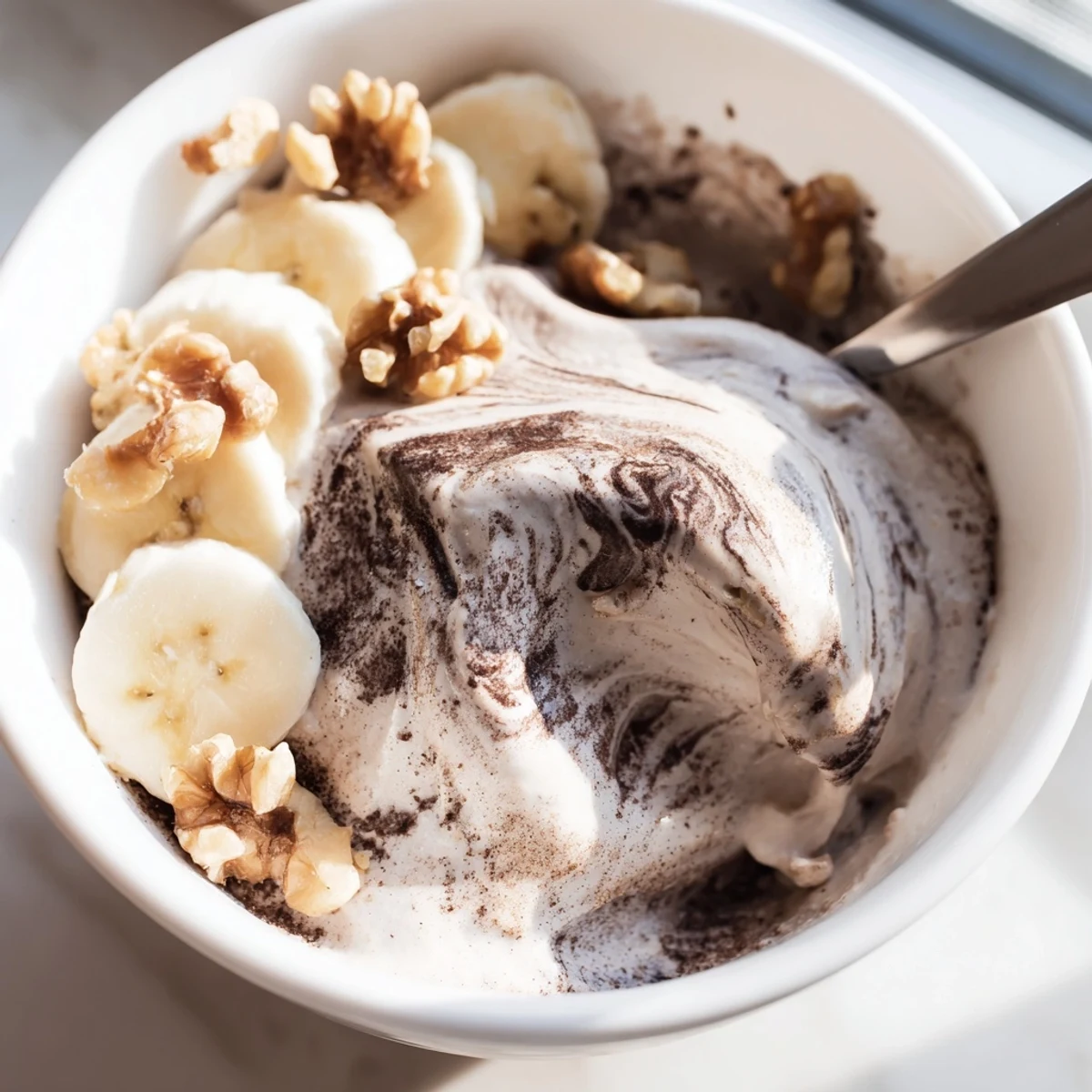 Whipped frozen banana healthy nice cream in a glass bowl with colorful fruit garnish