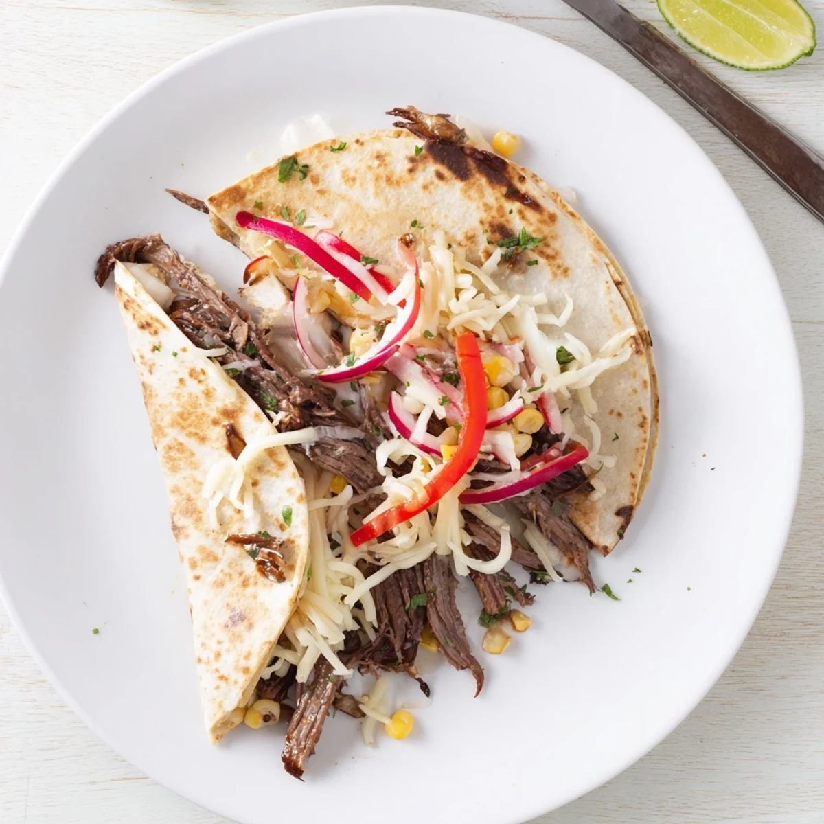 Warm Sweet Savory Beef Quesadillas Recipe wedges with sour cream, lime, cilantro garnish  