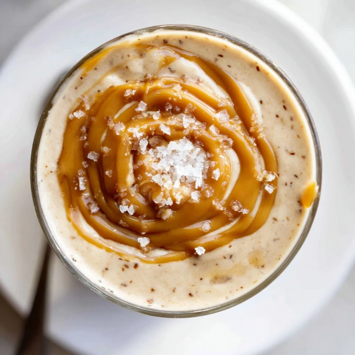Close-up of frothy Salted Caramel Protein Smoothie garnished with almond butter swirl