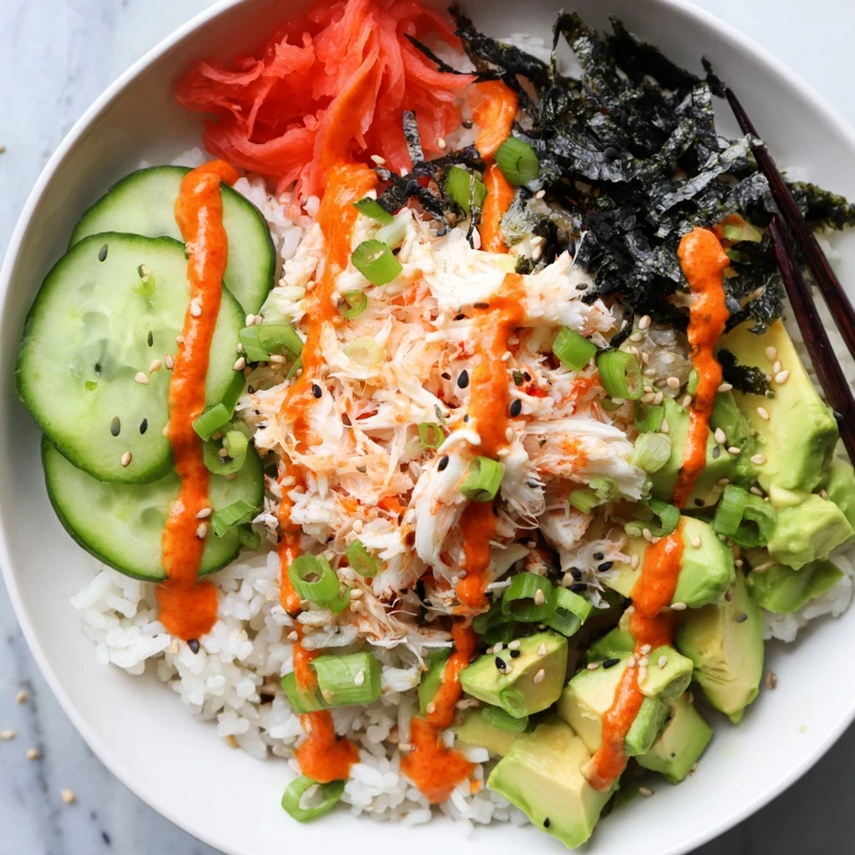 Vibrant California roll sushi bowl featuring fluffy rice, shredded crab, creamy avocado, crisp cucumber, and nori strips drizzled with spicy mayo