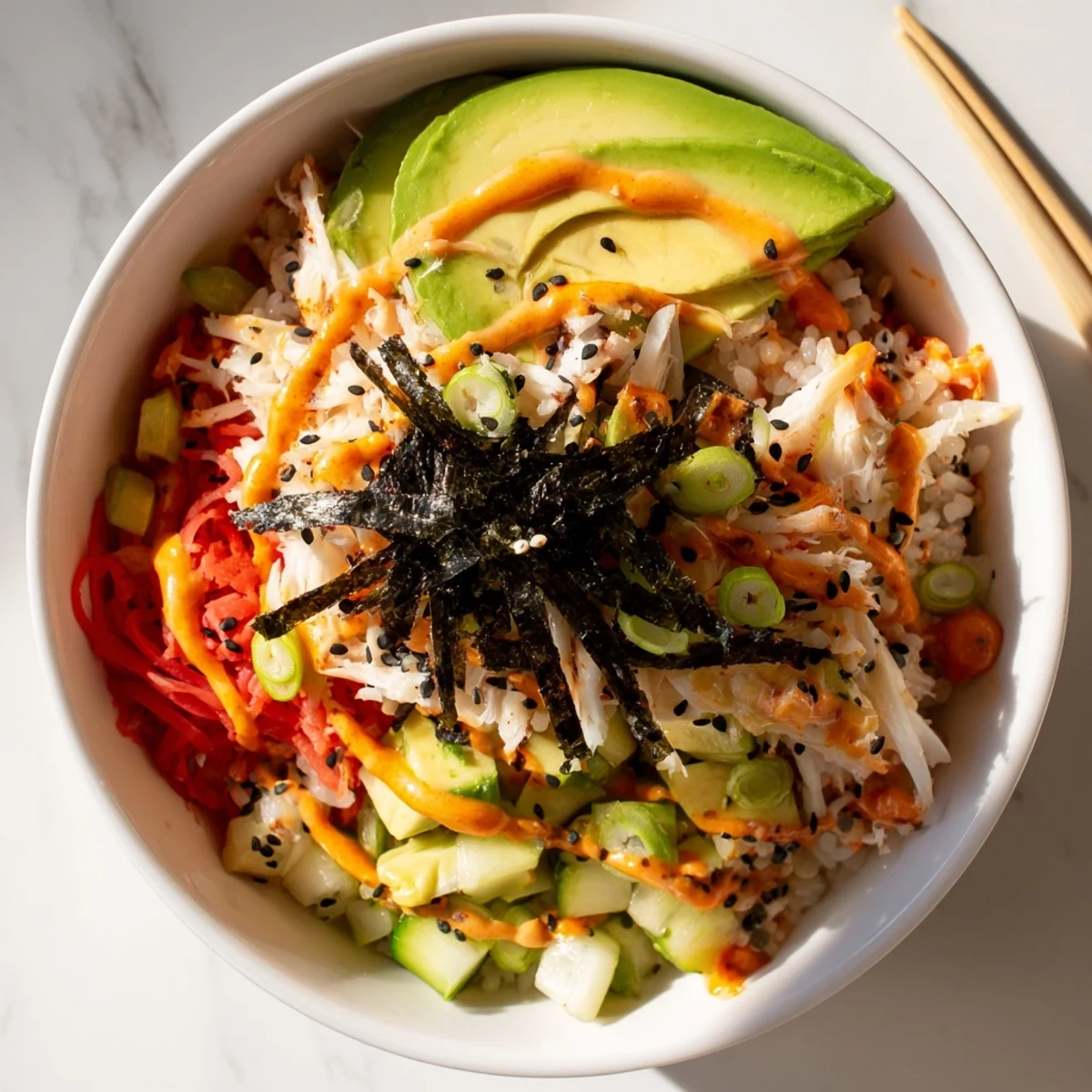 Deconstructed California roll sushi bowl arranged with seasoned rice, diced avocado, cucumber, imitation crab, and toasted sesame seeds