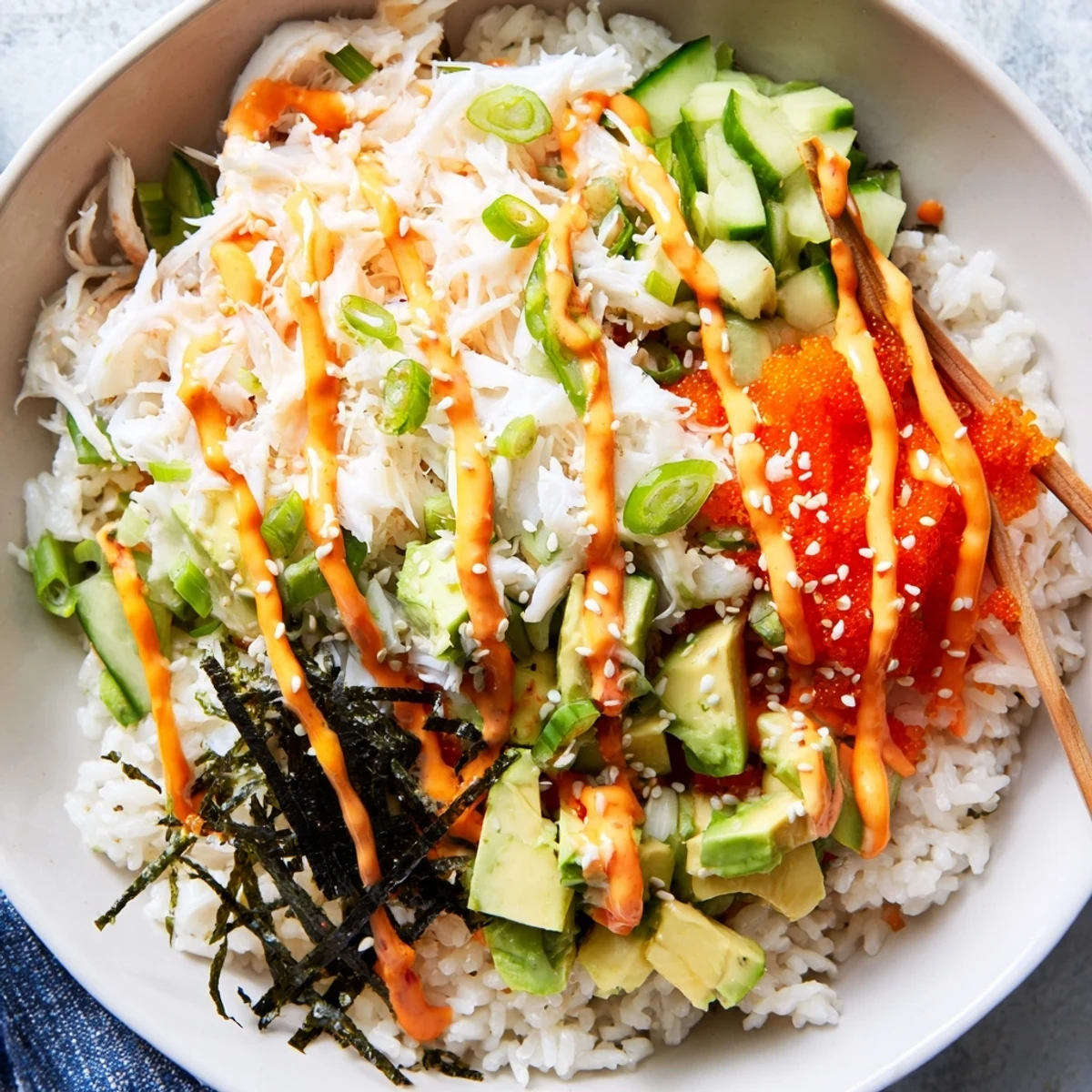 Colorful California roll sushi bowl topped with fresh crab, avocado chunks, pickled ginger, nori ribbons, and spicy Japanese mayonnaise
