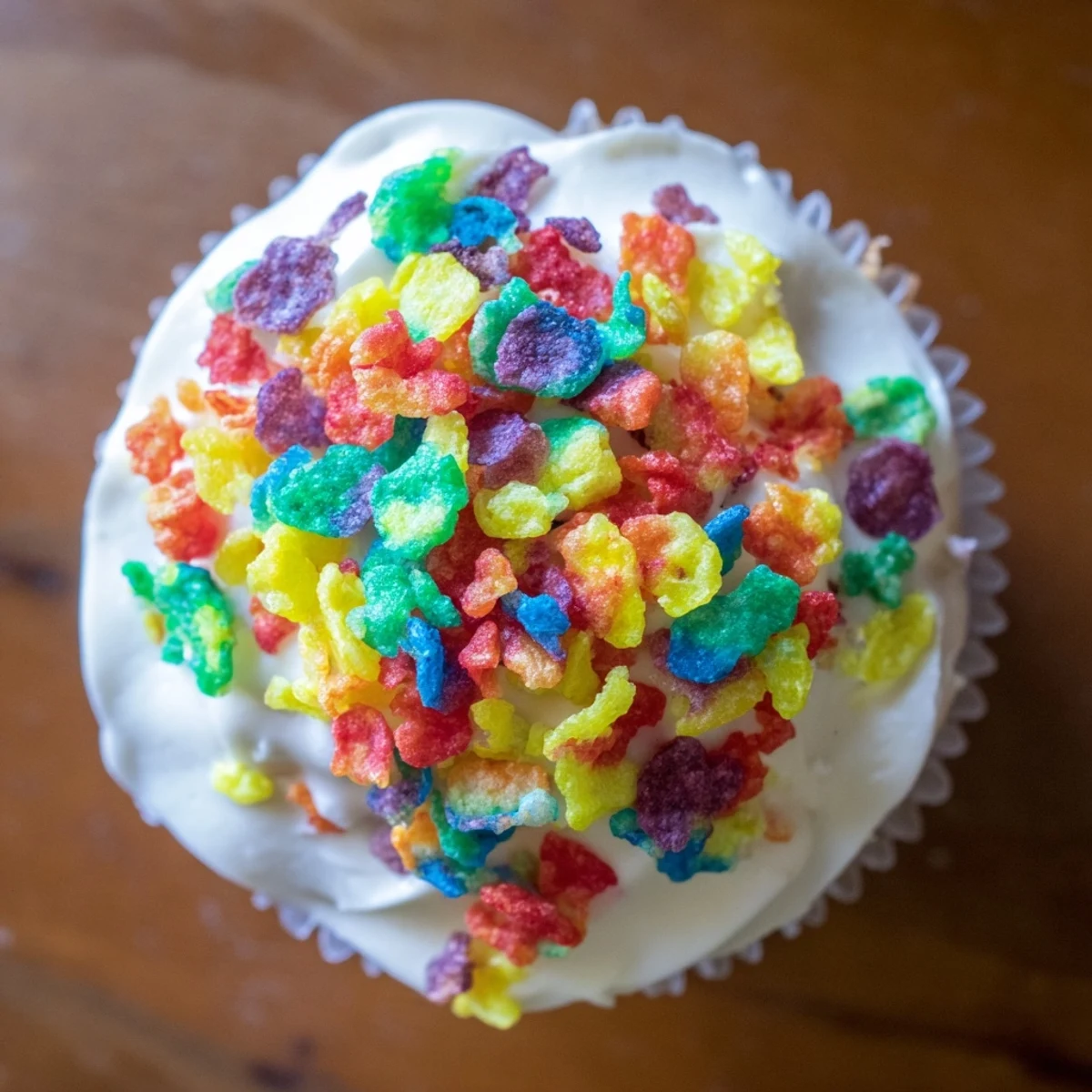 Fruity Pebbles cereal frosting swirled onto vanilla cupcakes with colorful cereal sprinkles on top