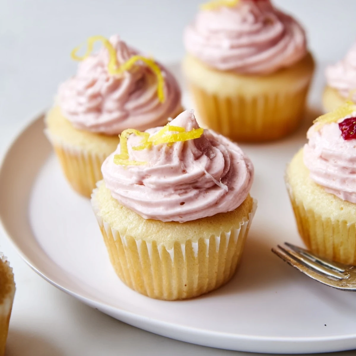 Fresh strawberry lemonade cupcakes topped with pink buttercream frosting and diced strawberries