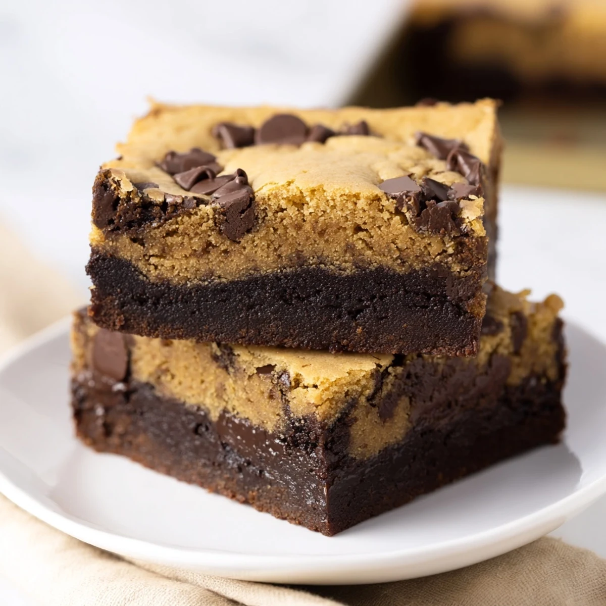 Fudgy chewy brookies stacked on a white plate with chocolate chunks visible throughout