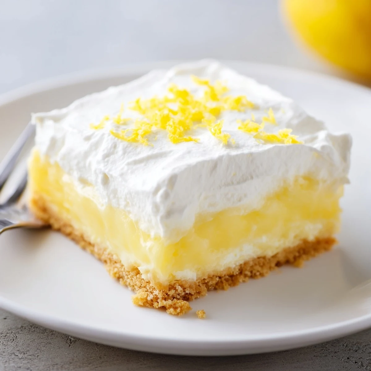 Lemon Lush Cake with creamy lemon layer and whipped topping, chilled.