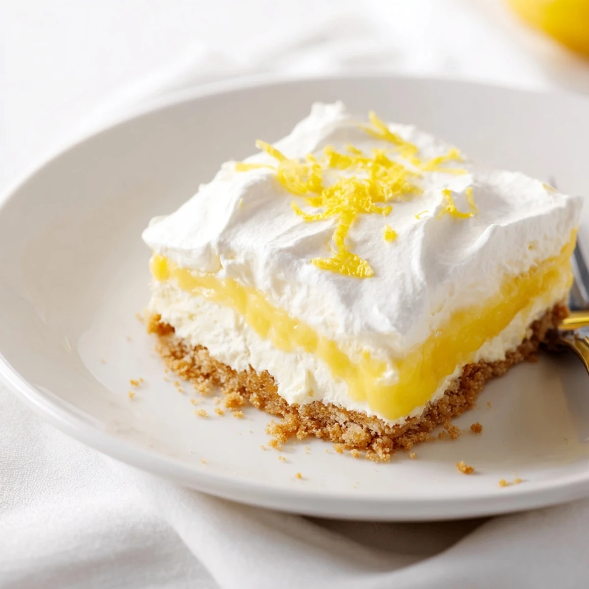 Slice of Lemon Lush Cake showing buttery crust, tangy filling, airy topping.