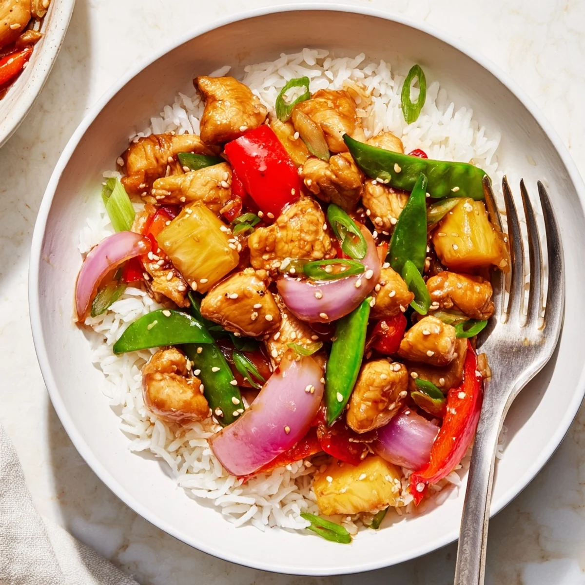 Juicy glazed pineapple chicken rice bowl garnished with spring onions and sesame seeds