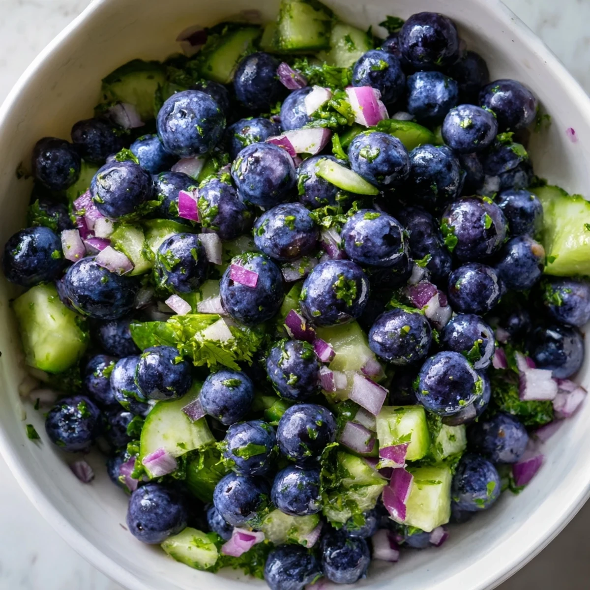 Vibrant blueberry cucumber salsa topped with lime zest and served beside grilled fish
