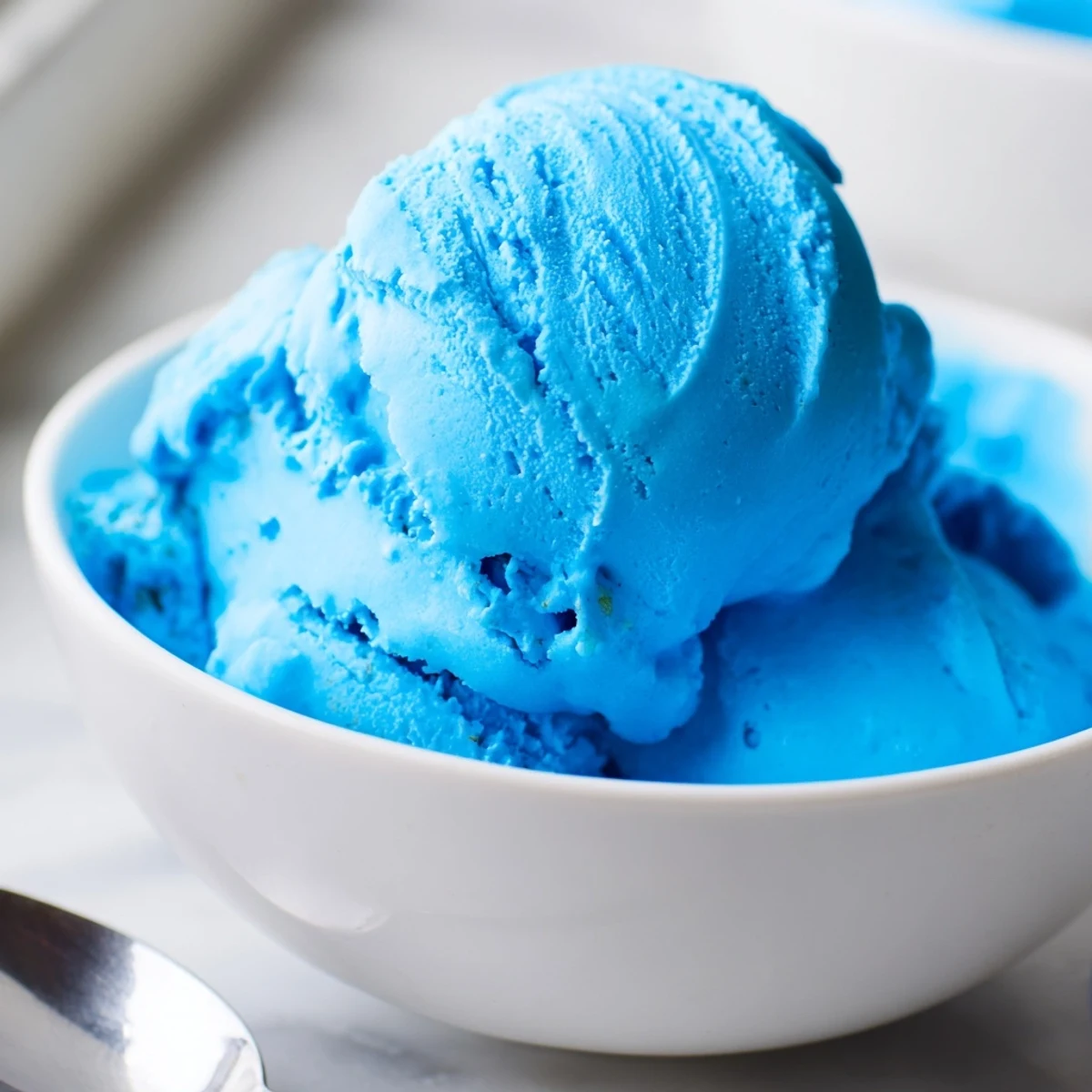 Vibrant blue moon ice cream swirling smoothly in a frozen bowl topped with whipped cream