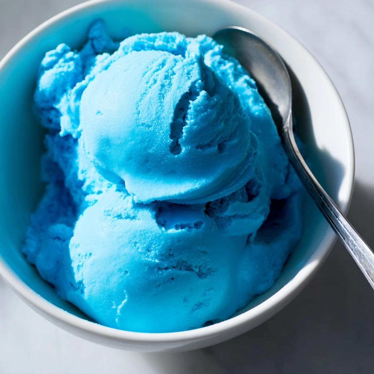 Homemade Blue Moon Ice Cream in a sunlit summer scene with a silver scoop nearby