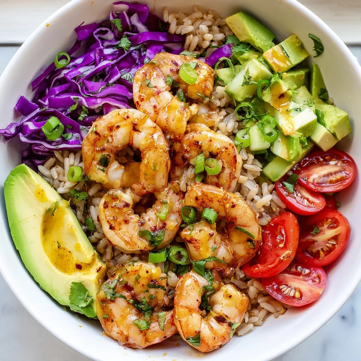 Golden seared shrimp grain bowl topped with fresh avocado and colorful crisp vegetables