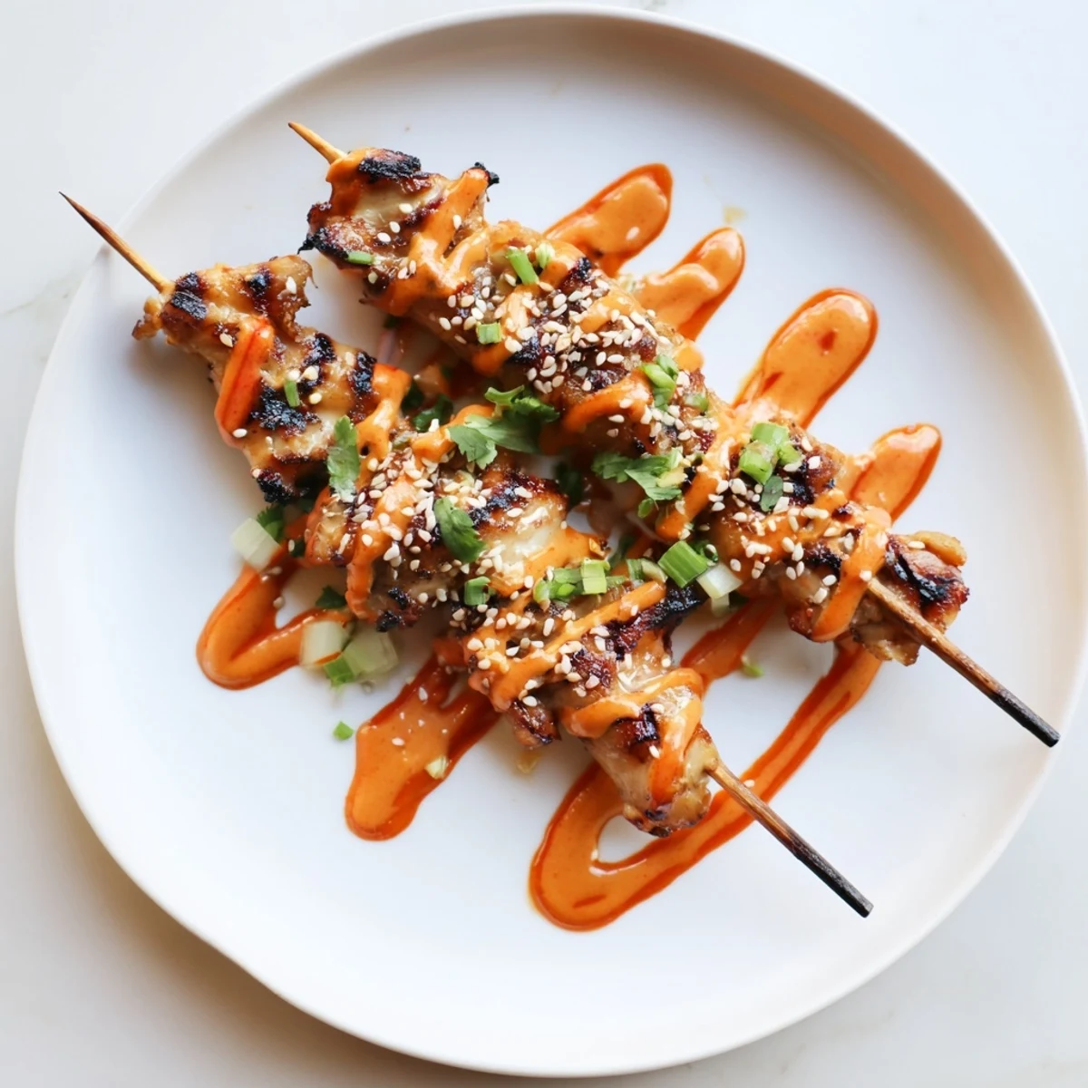 Sizzling Bang Bang Chicken Skewers on a platter coated in sweet chili cream sauce