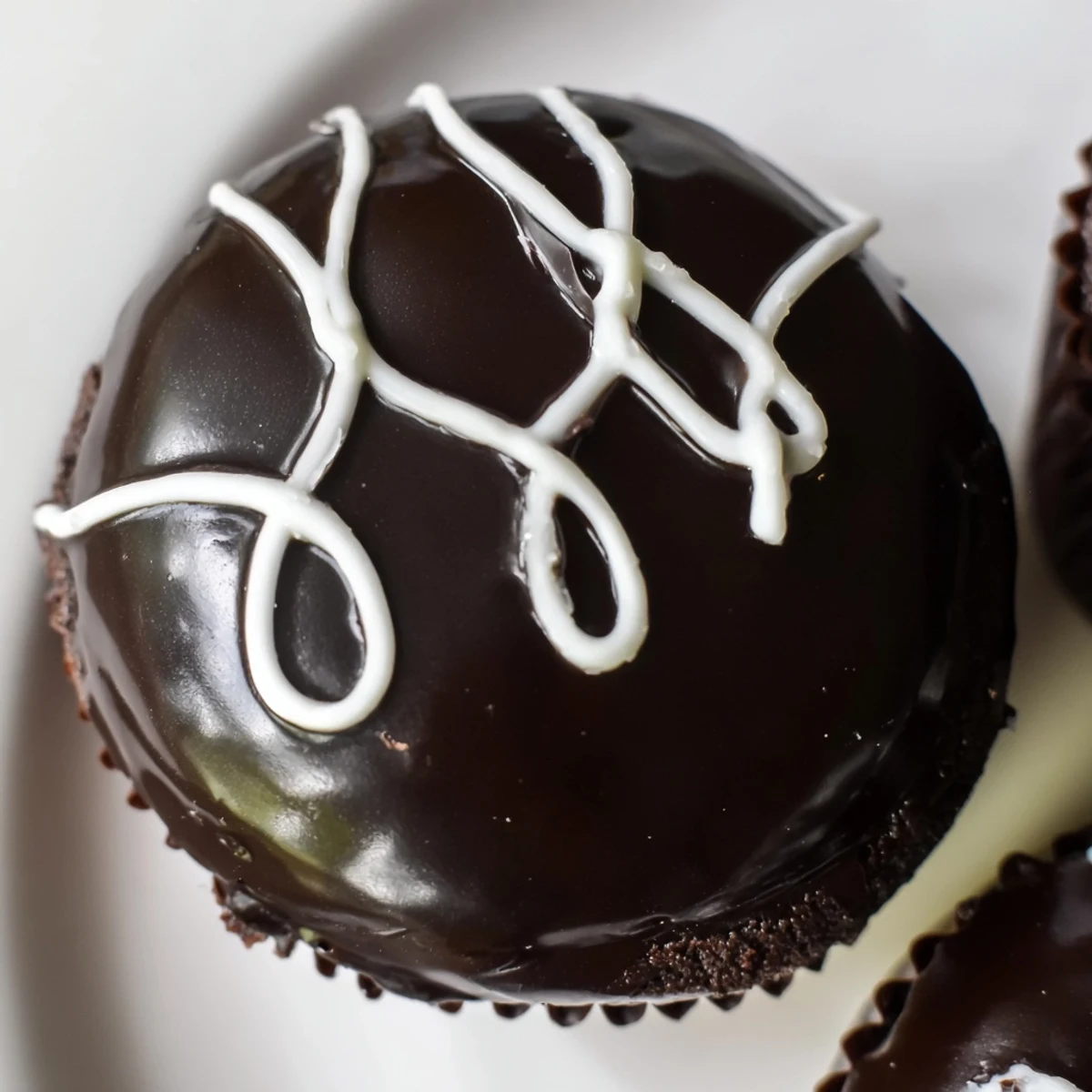 Homemade Hostess Cupcakes with glossy ganache and signature white swirl on top