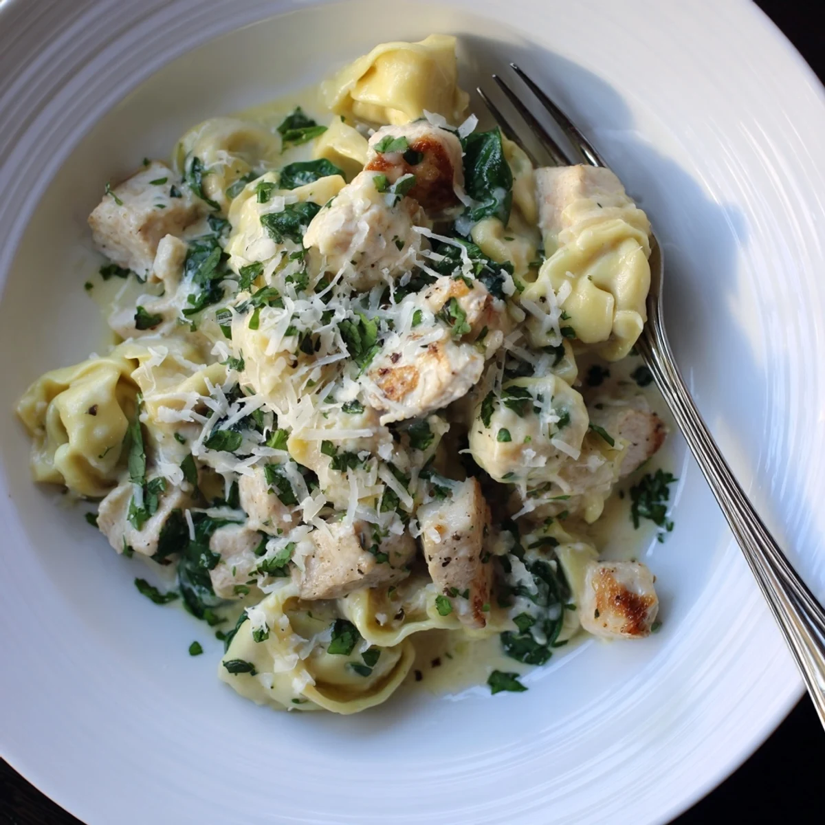 Steaming bowl of Creamy Garlic Chicken Tortellini with Spinach garnished with fresh parsley
