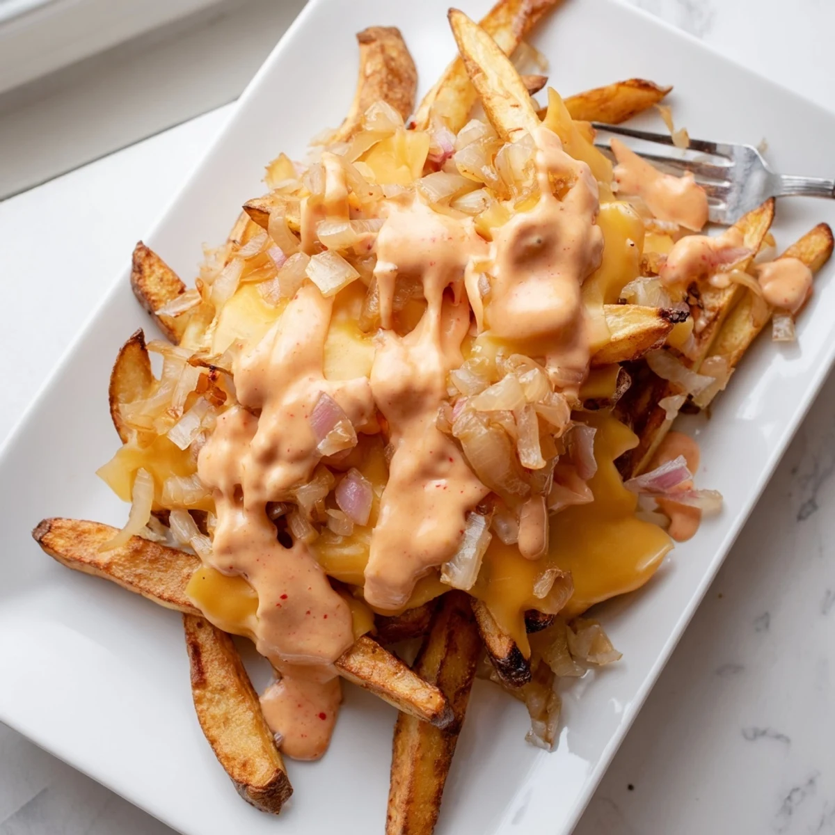 Steaming plate of In-N-Out Animal Style fries draped in gooey melted cheese