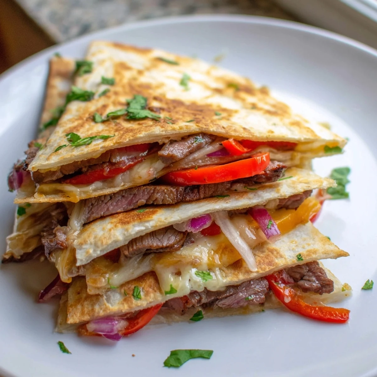 Steak quesadillas cut into triangles garnished with fresh cilantro sour cream and salsa