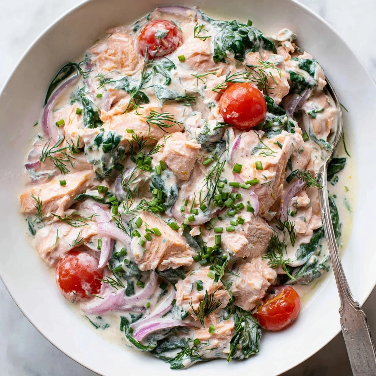 Creamy leftover salmon recipe served in a golden skillet with vibrant spinach and tomatoes