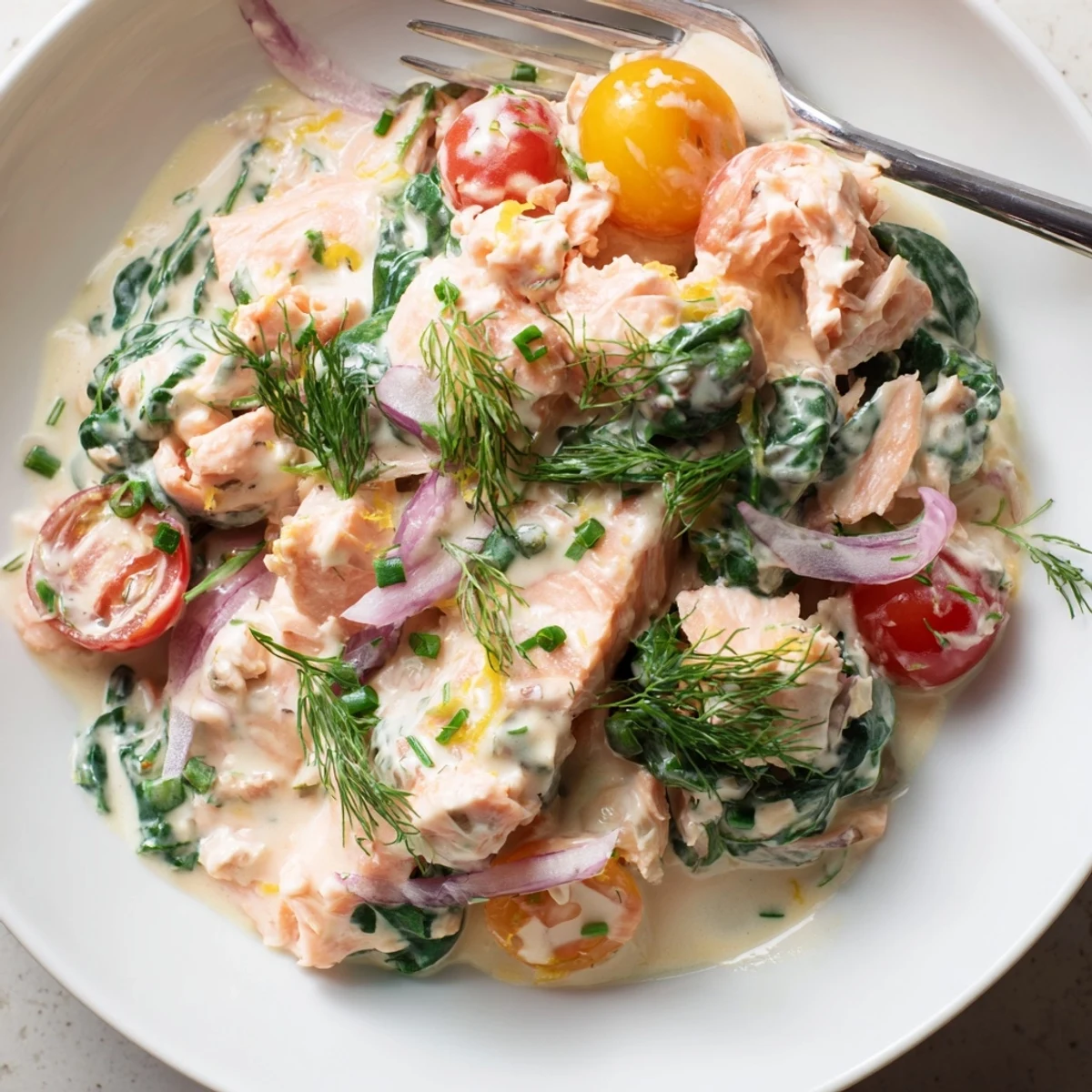 Steaming plate of healthy creamy leftover salmon over quinoa with bright lemon and dill