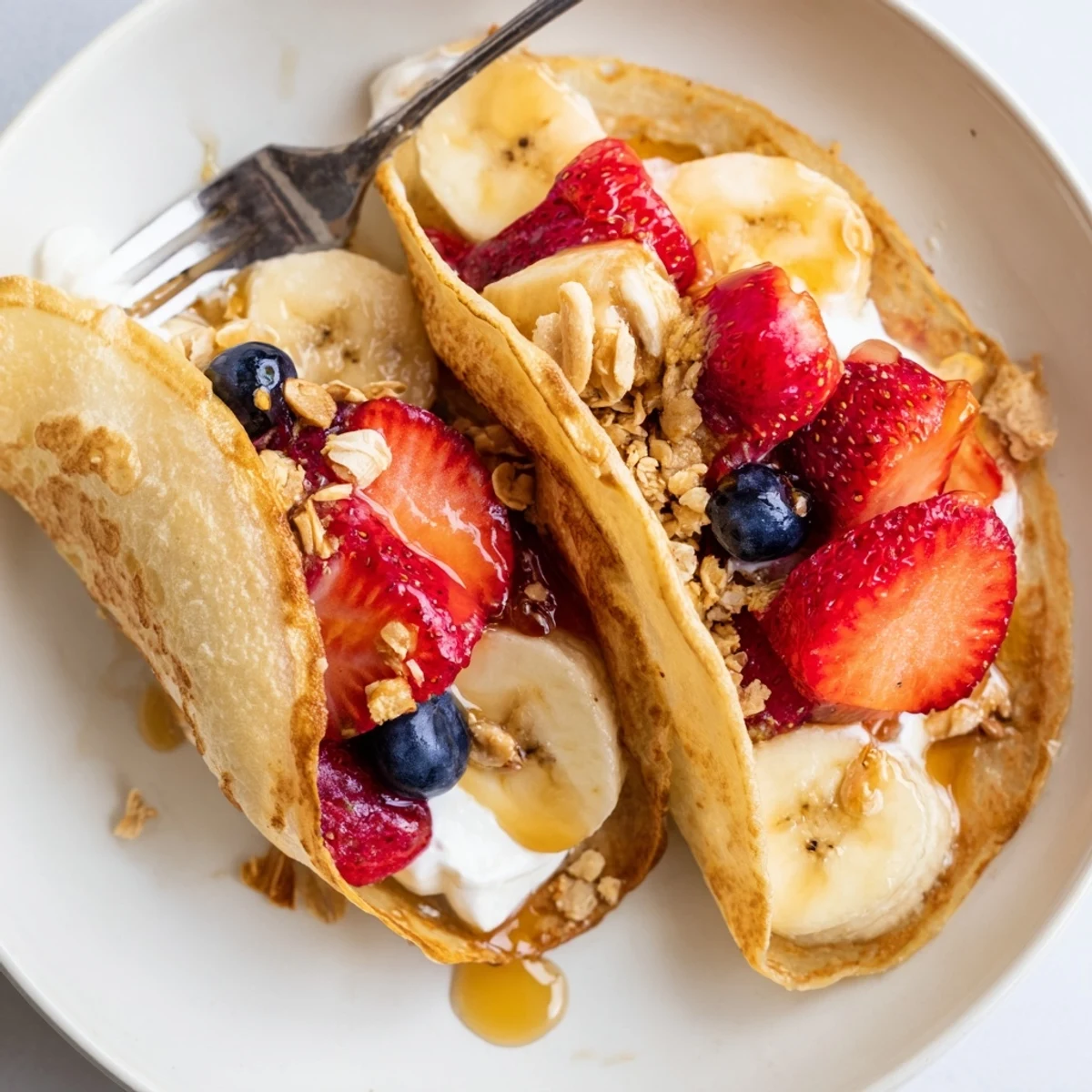 Golden pancake tacos filled with fresh strawberries and drizzled maple syrup on a rustic plate
