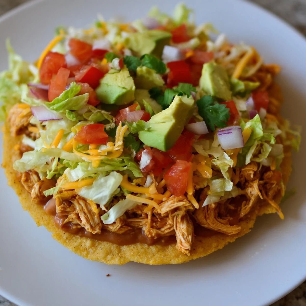 Golden crispy chicken tostadas topped with fresh veggies and creamy cheese.  