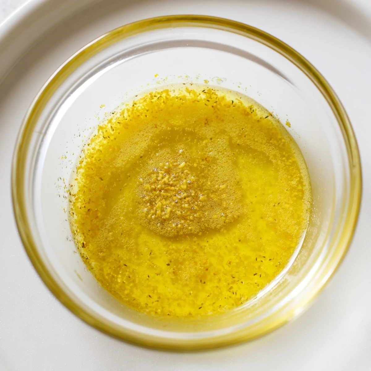 Glass jar of lemon vinaigrette dressing recipe drizzled over fresh green salad.  