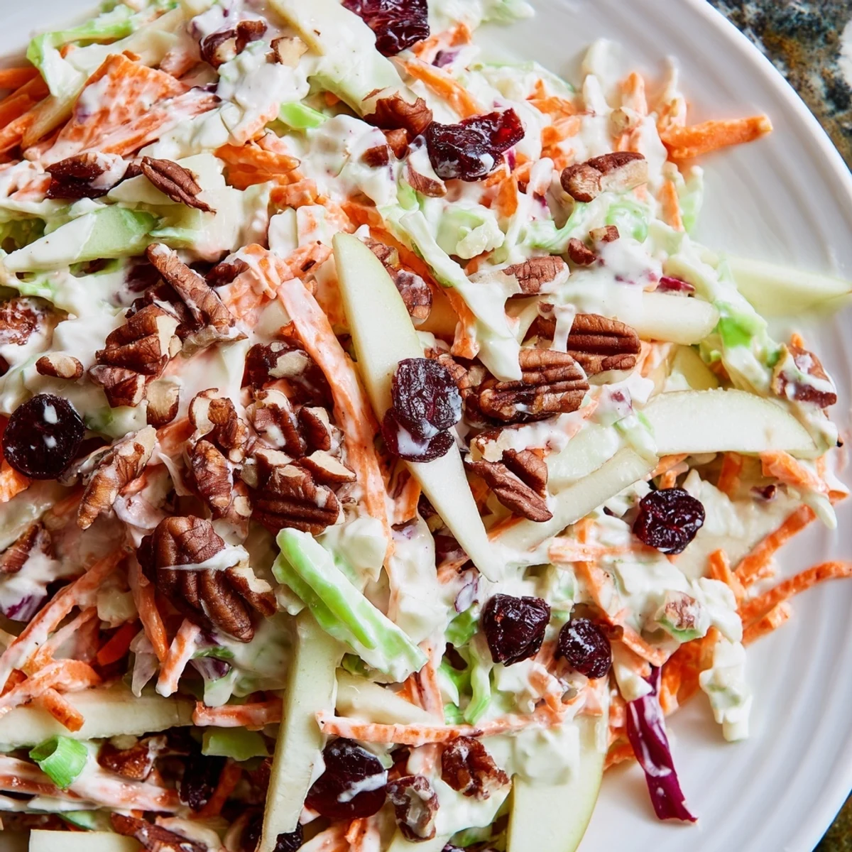 Colorful Cranberry Apple Coleslaw featuring shredded carrots, crisp apple slices, and dried cranberries.