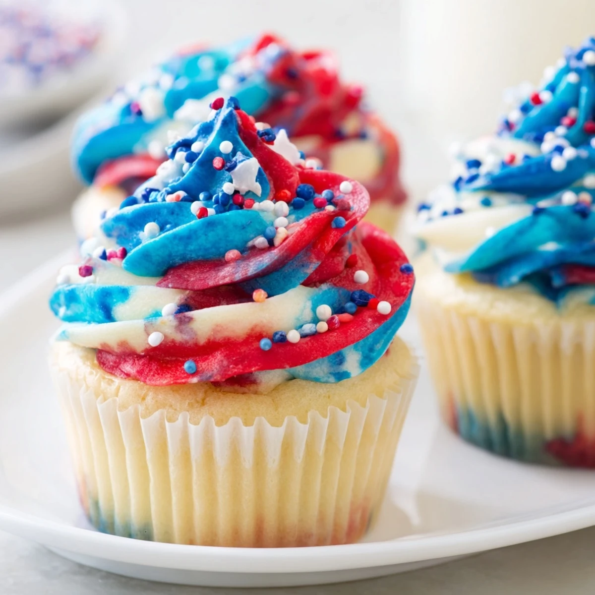 Colorful Fourth of July tie dye cupcakes with swirled red white and blue frosting.