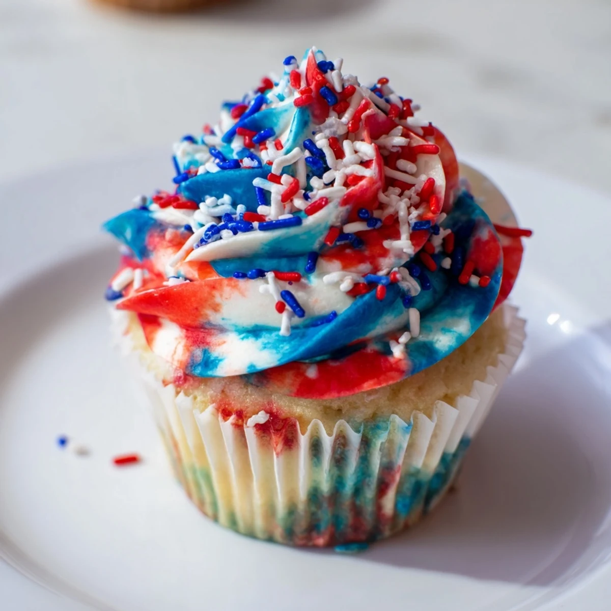 Moist vanilla July tie dye cupcakes topped with vibrant patriotic buttercream swirls.