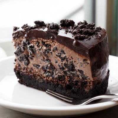 Rich Oreo chocolate cheesecake with a thick cookie crust topped with glossy ganache